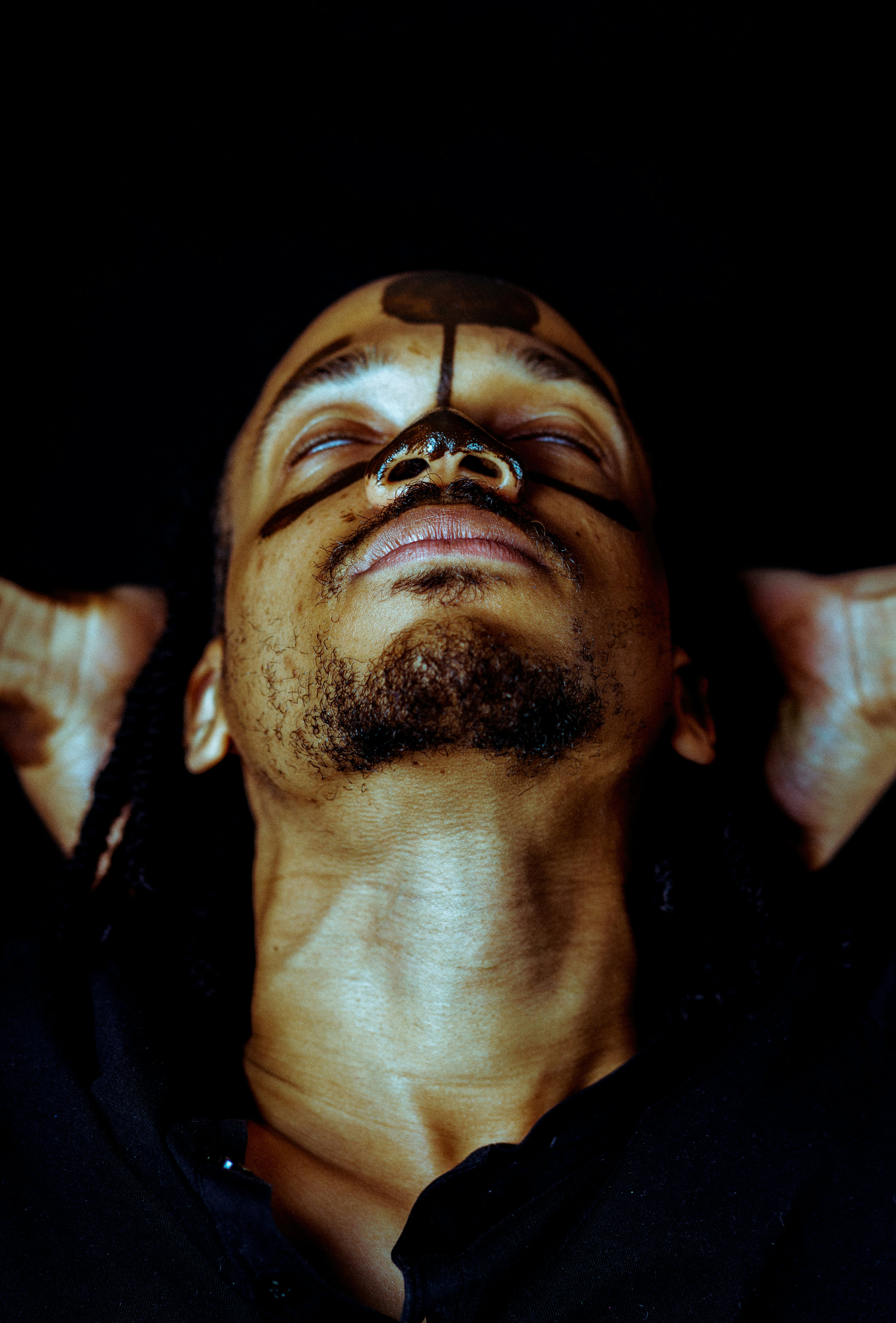 man wearing black top with black paint on his face